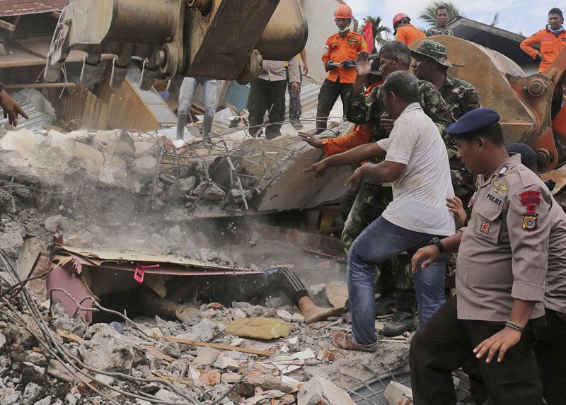 Rescuers recover the body of a victim from a collapsed building