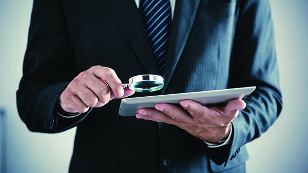 Man with magnifying glass looking at tablet