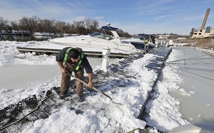 Man shoveling snow off dock on James River, VA