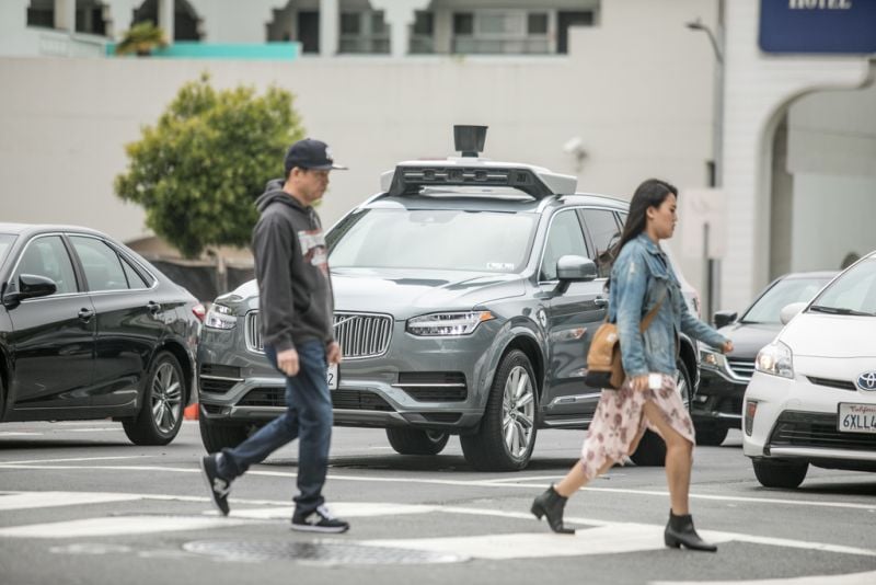 Uber car waiting while pedestrians cross street