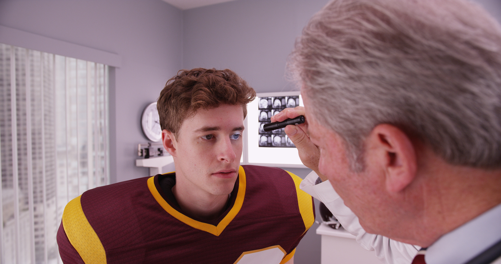 doctor examining a football player for a concussion