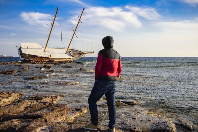 shipwreck near shore with man watching