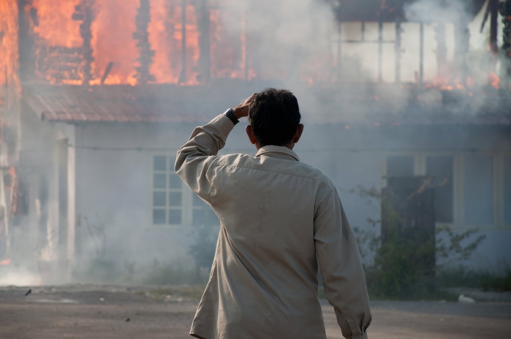 Man looking at burning house