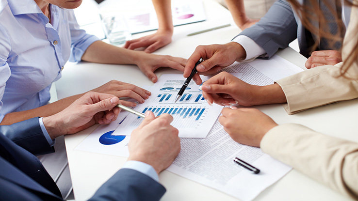 Group of people around a conference table reviewing documents