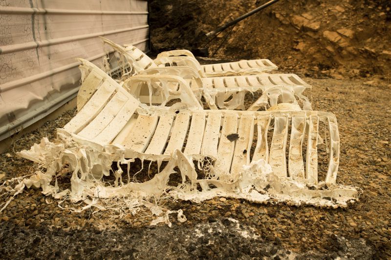 Melted lawn chairs rest outside a residence leveled by the Detwiler fire