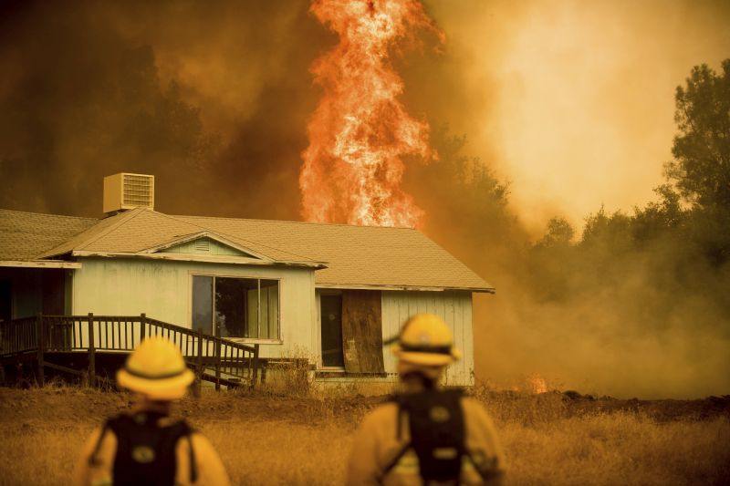 flames rise behind a vacant house 