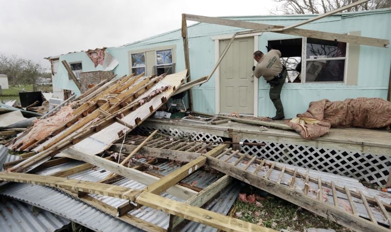 An official climbs through a window as he checks home damaged by Hurricane Harvey