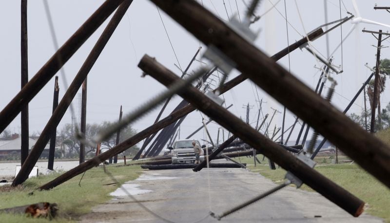 A driver works his way through a maze of fallen utility poles damaged in the wake of Hurricane Harvey