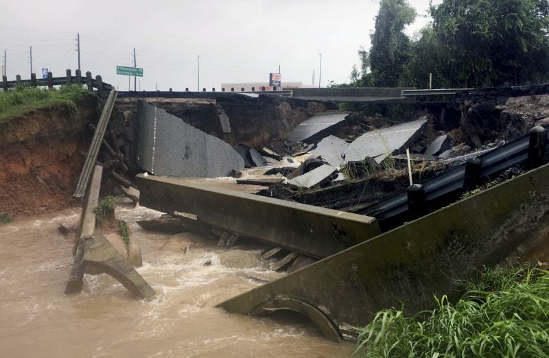 Waters rush from a large sinkhole on Highway FM 762 in Rosenberg, Texas