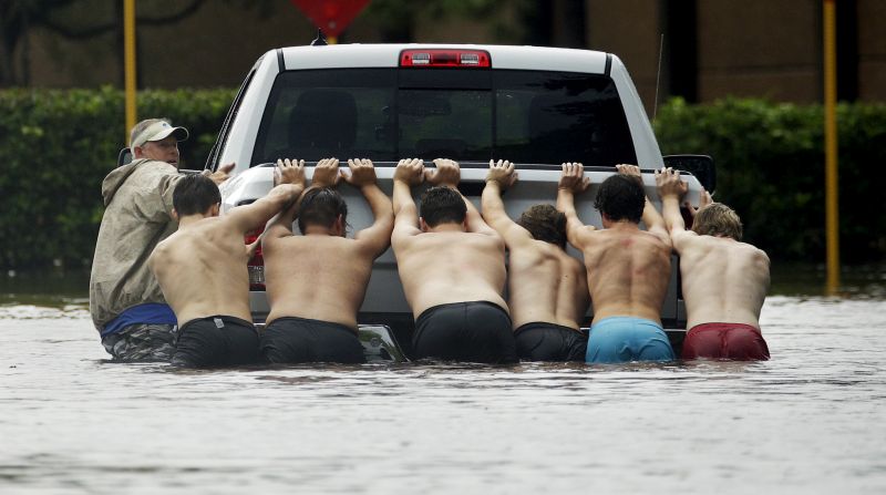 People push a stalled pickup to through a flooded street in Houston, after Tropical Storm Harve