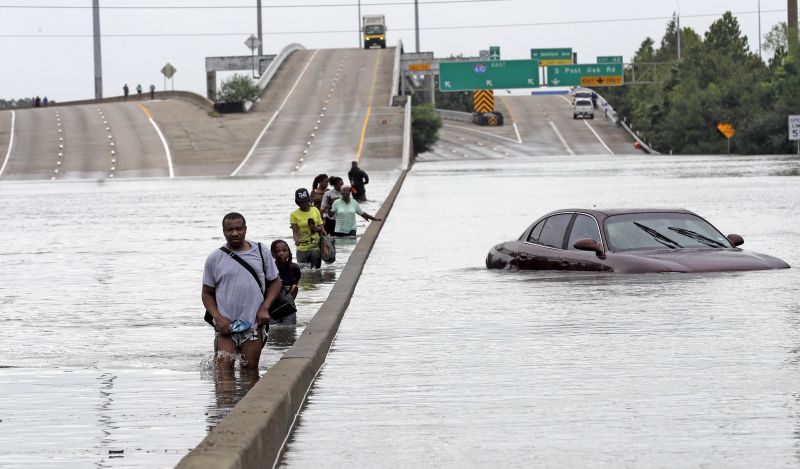 Evacuees wade down a flooded section of Interstate 610 as floodwaters from Tropical Storm Harvey rise