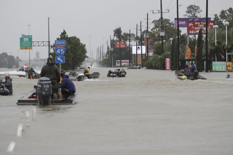 Volunteer rescue boats make their way into a flooded subdivision to rescue stranded residents 