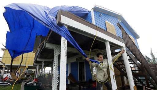 Man trying to tarp his home against further damage