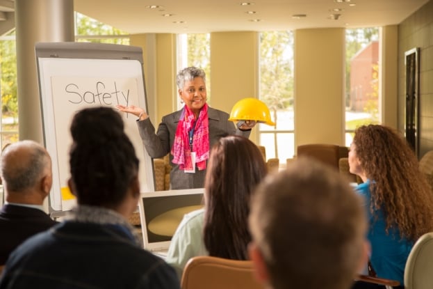 Safety meeting led by African-American woman holding hard hat