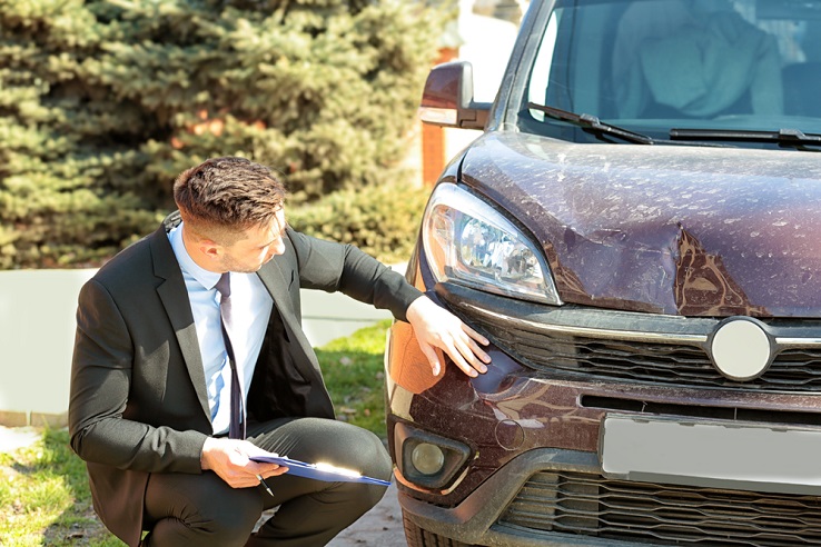 Young adjuster examining a car