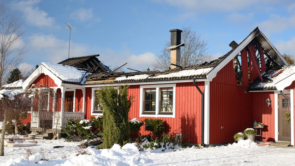 Red ranch-style house with fire-damaged roof