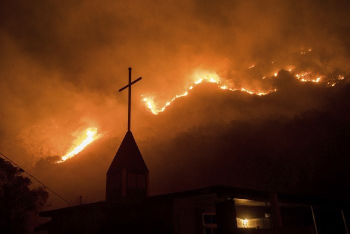 Flames from a wildfire advance down a hillside near the Springs of Life Church in Casitas Springs, Calif.