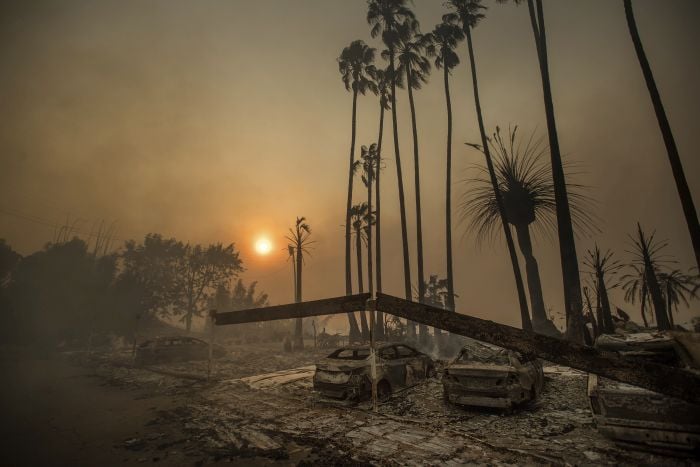 Smoke rises behind a leveled apartment complex as a wildfire burns in Ventura, Calif.