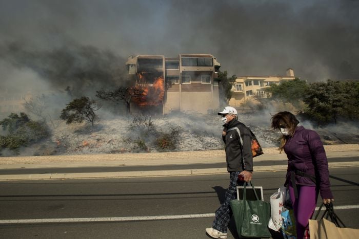 James and Josie Ralstin carry belongings from their Ventura, Calif., home as flames from a wildfire consume another residence