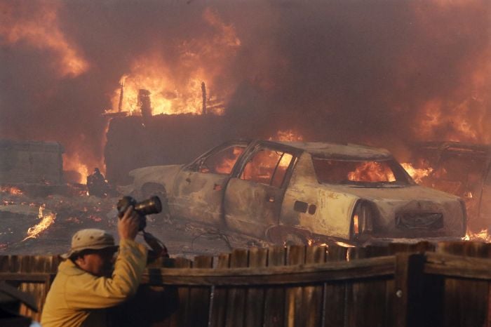 A news photographer takes pictures of a wildfire in the Lake View Terrace area of Los Angeles