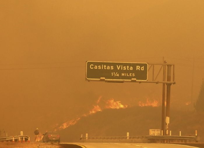 Flames and smoke shroud State Route 33 as a wildfire burns in Ventura, Calif.