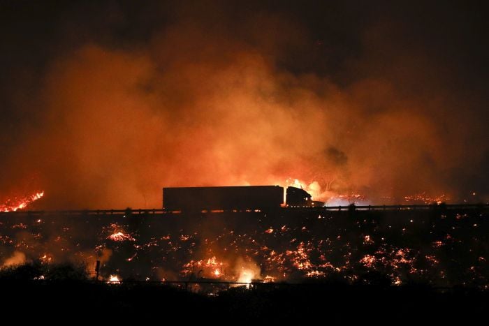 A truck drives along the 101 Freeway as a wildfire continues to burn 