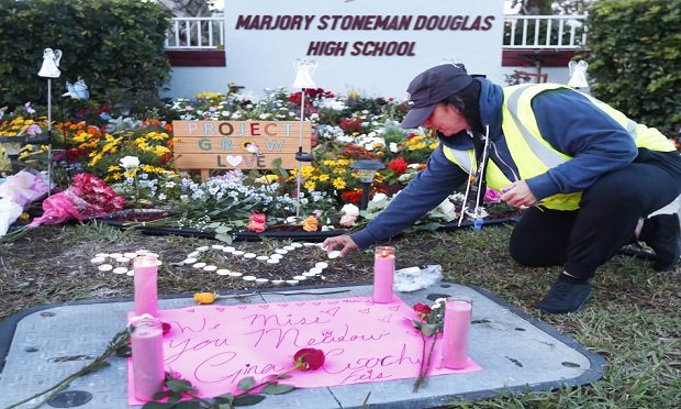 School crossing guard Wendy Behrend lights a candle at a memorial outside Marjory Stoneman Douglas High School during the one-year anniversary of the school shooting, Thursday, Feb. 14, 2019, in Parkland, Fla. (AP Photo/Wilfredo Lee)