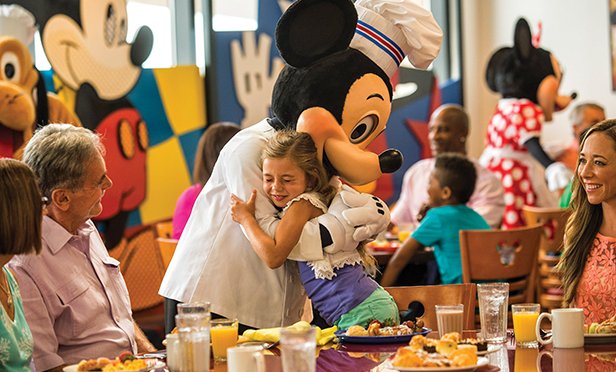 Mickey Mouse hugs a guest.