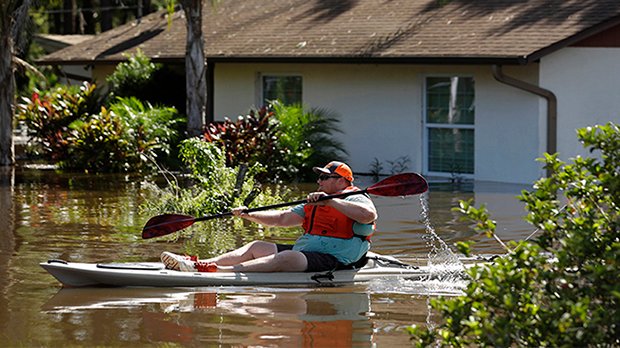 Man-paddling-kayak-on-flooded-street