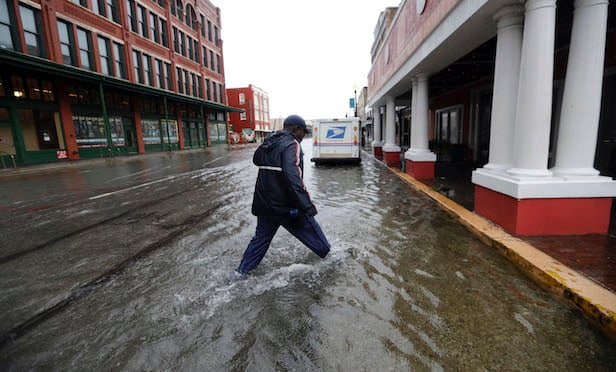 A postman walks through streets flooded by Tropical Depression Imelda as he deliver mail on Wednesday, Sept. 18, 2019, in Galveston, Texas. (AP Photo/David J. Phillip)