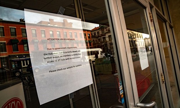 A sign notifying facility closure hangs on a window of a New York Sport Club (NYSC) location in Hoboken, New Jersey, U.S., on Monday, March 16, 2020. (David 'Dee' Delgado/Bloomberg)