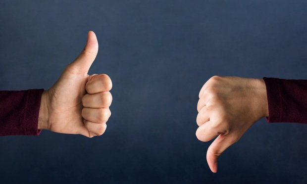 Two thumbs, one giving a thumbs up and the other a thumbs down, against a dark blue background.