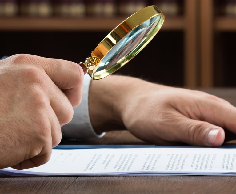 A person holds a magnifying glass as they look at documents.