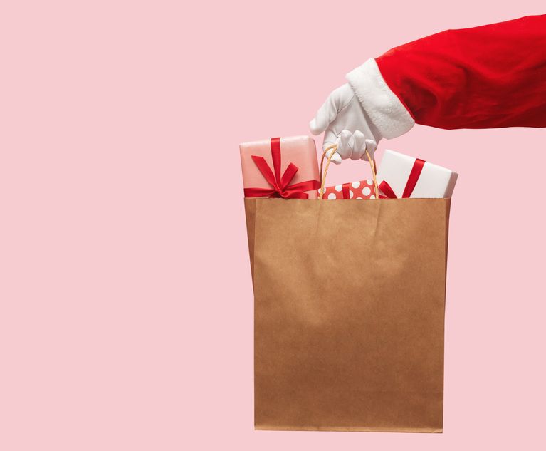 Santa Claus hand holding brown shopping bag with gift boxes on isolated background. Black Friday, Sales, Giving Gift for Christmas and New Year 2019 concepts. Credit: eggeeggjiew/Adobe Stock