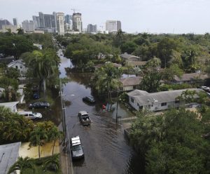 FILE - Trucks and a resident on foot make their way through receding floodwaters in the Sailboat Bend neighborhood of Fort Lauderdale, Fla., April 13, 2023. Over 25 inches of rain fell in South Florida since Monday, causing widespread flooding. (Credit; Rebecca Blackwell/AP)