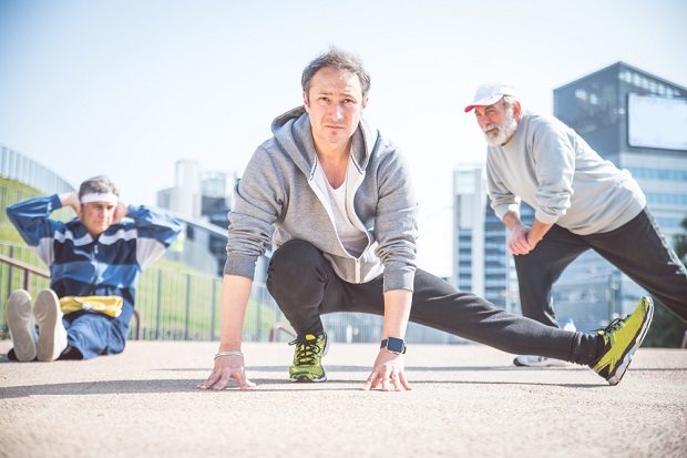older man stretching with friends before going for a run