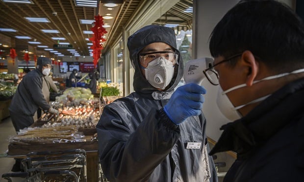 A Chinese worker checks the temperature of a customer as he wears a protective suit and mask at a supermarket on February 11, 2020 in Beijing, China. The number of cases of a deadly new coronavirus rose to more than 42000 in mainland China Tuesday, days after the World Health Organization (WHO) declared the outbreak a global public health emergency. China continued to lock down the city of Wuhan in an effort to contain the spread of the pneumonia-like disease which medicals experts have confirmed can be passed from human to human. In an unprecedented move, Chinese authorities have put travel restrictions on the city which is the epicentre of the virus and municipalities in other parts of the country affecting tens of millions of people. The number of those who have died from the virus in China climbed to over 1000 on Tuesday, mostly in Hubei province, and cases have been reported in other countries including the United States, Canada, Australia, Japan, South Korea, India, the United Kingdom, Germany, France and several others. The World Health Organization has warned all governments to be on alert and screening has been stepped up at airports around the world. Some countries, including the United States, have put restrictions on Chinese travellers entering and advised their citizens against travel to China. (Photo by Kevin Frayer/Getty Images)