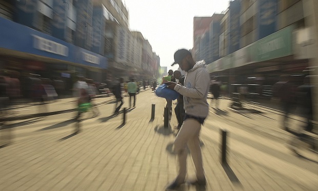 A man using his mobile phone walks along a street in down town Nairobi on July 24, 2019. (Photo by SIMON MAINA / AFP) (Photo credit should read SIMON MAINA/AFP via Getty Images)