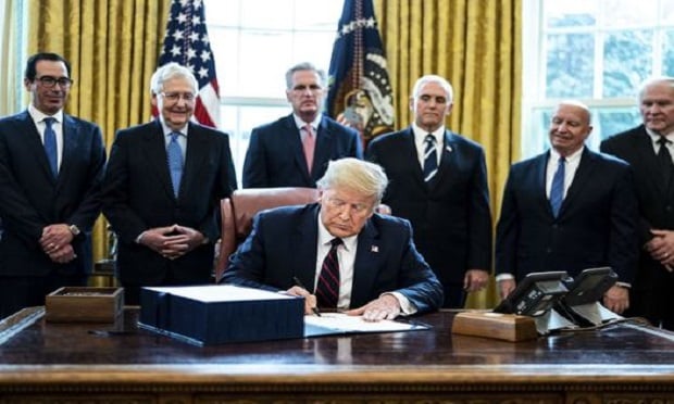 U.S. President Donald Trump signs the H.R. 748, Coronavirus Aid, Relief, and Economic Security (CARES) Act, in the Oval Office of the White House in Washington, D.C., U.S., on Friday, March 27, 2020. Trump signed the largest stimulus package in U.S. history today, a $2 trillion bill intended to rescue the coronavirus-battered economy after the House approved it earlier. (Photo: Erin Schaff/The New York Times/Bloomberg)