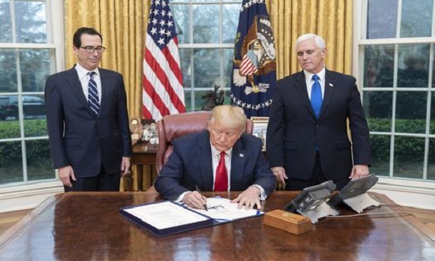 President Donald J. Trump, joined by Vice President Mike Pence and Treasury Secretary Steven Mnuchin, signs H.R. 6201, the Families First Coronavirus Response Act on Wednesday, March 18, 2020, in the Oval Office of the White House. (Official White House Photo by Shealah Craighead)