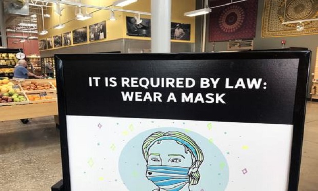 A sign reminds customers to wear a protective mask to stem the spread of the coronavirus at a MOM’s Organic Market in Baltimore on June 16, 2020. (Photo: Diego M. Radzinschi/ALM)