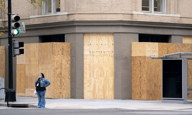 A pedestrian wearing a protective mask in front of boarded up businesses in Washington, D.C., U.S., on Wednesday, Oct. 28, 2020. After being caught off guard during nationwide social unrest this summer and suffering millions in damages, retailers are prepping for another possible bout of vandalism on Election Day. (Photo: Stefani Reynolds/Bloomberg)