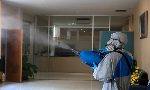 A worker in a hazmat suit disinfects an office to prevent the spread of the coronavirus. (Photo: Shutterstock)