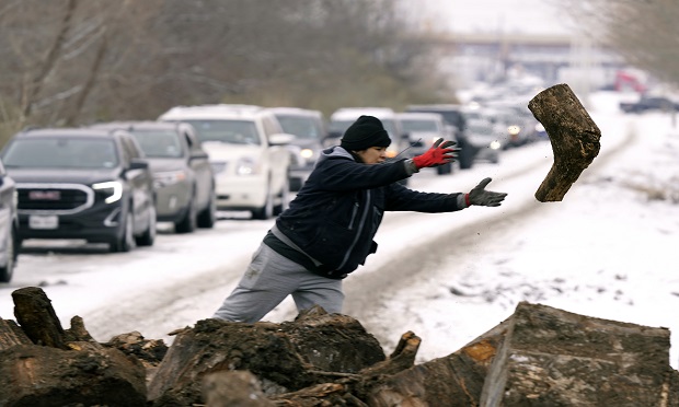 In light of widespread power outages, Texans lined up to collect firewood in Dallas on Wed., Feb. 17, 2021. Groups of thirteen were allowed six minutes to load as much wood as they could carry away from the recycling center. Here, Michelle Terrazas tosses a log off the pile. (AP Photo/LM Otero)