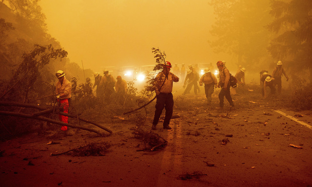 Firefighters battling the Dixie Fire clear Highway 89 after a burned tree fell across the roadway in Plumas County, Calif., on Friday, Aug. 6, 2021.