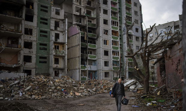A man carrying his belongings leaves his house as he walks past buildings destroyed by artillery in Chernihiv on Thursday, April 21, 2022. Photo: Emilio Morenatti/AP