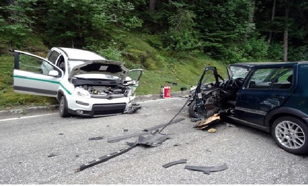 Two cars damaged in a head-on collision on a road.