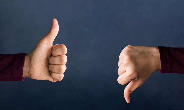 Two thumbs, one giving a thumbs up and the other a thumbs down, against a dark blue background.