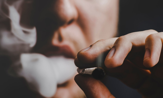 Close up photo of a person smoking a marijuana cigarette. In both cases, a workers' compensation judge awarded the injured worker reimbursement for medicinal marijuana expenses incurred to treat their work-related injuries. In both cases, the Minnesota Workers' Compensation Court of Appeals upheld the decision of the judge and declined to address the conflict between state and federal law. (Credit: Dmytro Tyshchenko/Shutterstock.com) 