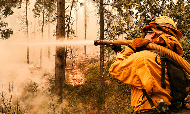 A firefighter works to control a backfire operation conducted to slow the advancement on a hillside during the Oak Fire in Mariposa County, California, US, on Sunday, July 24, 2022. A fast-moving wildfire near Yosemite National Park exploded in size Saturday into one of California's largest wildfires of the year, prompting evacuation orders for thousands of people and shutting off power to more than 2,000 homes and businesses. (Credit: David Odisho) 